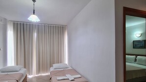 A hotel room with two beds, a bathroom visible through an open door, and a ceiling light. - Fora Apart Otel (Cesme)