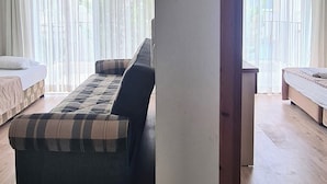 A room with a large bed, a sofa, and a wooden floor. - Fora Apart Otel (Cesme)