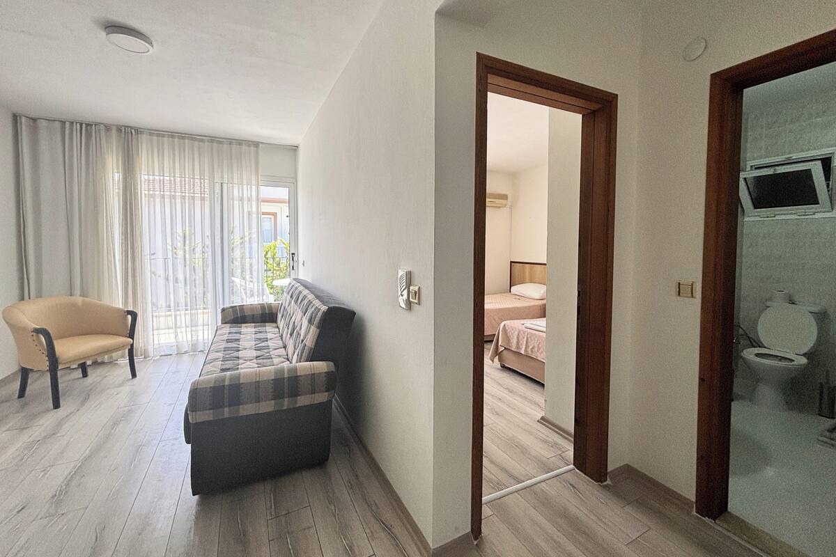 Habitación de hotel con sofá, una silla, cama y televisor en el baño.
