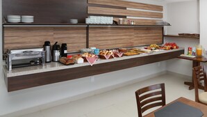 Una cucina moderna con bancone colazione, dotata di macchina del caffè, tostapane e diversi alimenti.