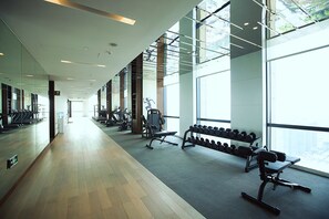 A gym with exercise equipment, large windows, and a wooden floor. - HUALUXE Wuxi Taihu by IHG (Wuxi)