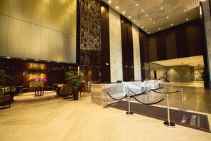 A spacious lobby with a reception desk, seating area, and a decorative wall. - HUALUXE Wuxi Taihu by IHG (Wuxi)