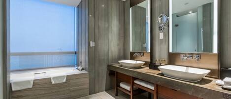 Un baño moderno con una bañera grande, dos lavamanos y un espejo amplio.