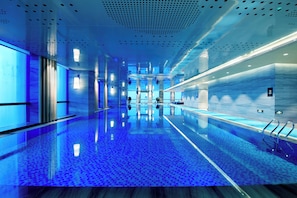 Un moderno vestíbulo de hotel con un estanque reflectante, una recepción y una vista despejada del área de la piscina.