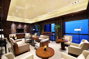 A modern hotel lobby with a large seating area, a bar, and large windows offering a view. - HUALUXE Wuxi Taihu by IHG (Wuxi)