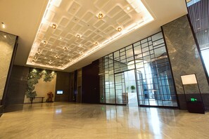 A spacious lobby with a high ceiling, modern lighting, and a large glass entrance. - HUALUXE Wuxi Taihu by IHG (Wuxi)