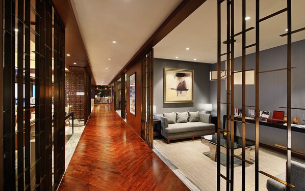 A hotel corridor with wooden flooring, a sofa, and a desk with a lamp. - HUALUXE Wuxi Taihu by IHG (Wuxi)