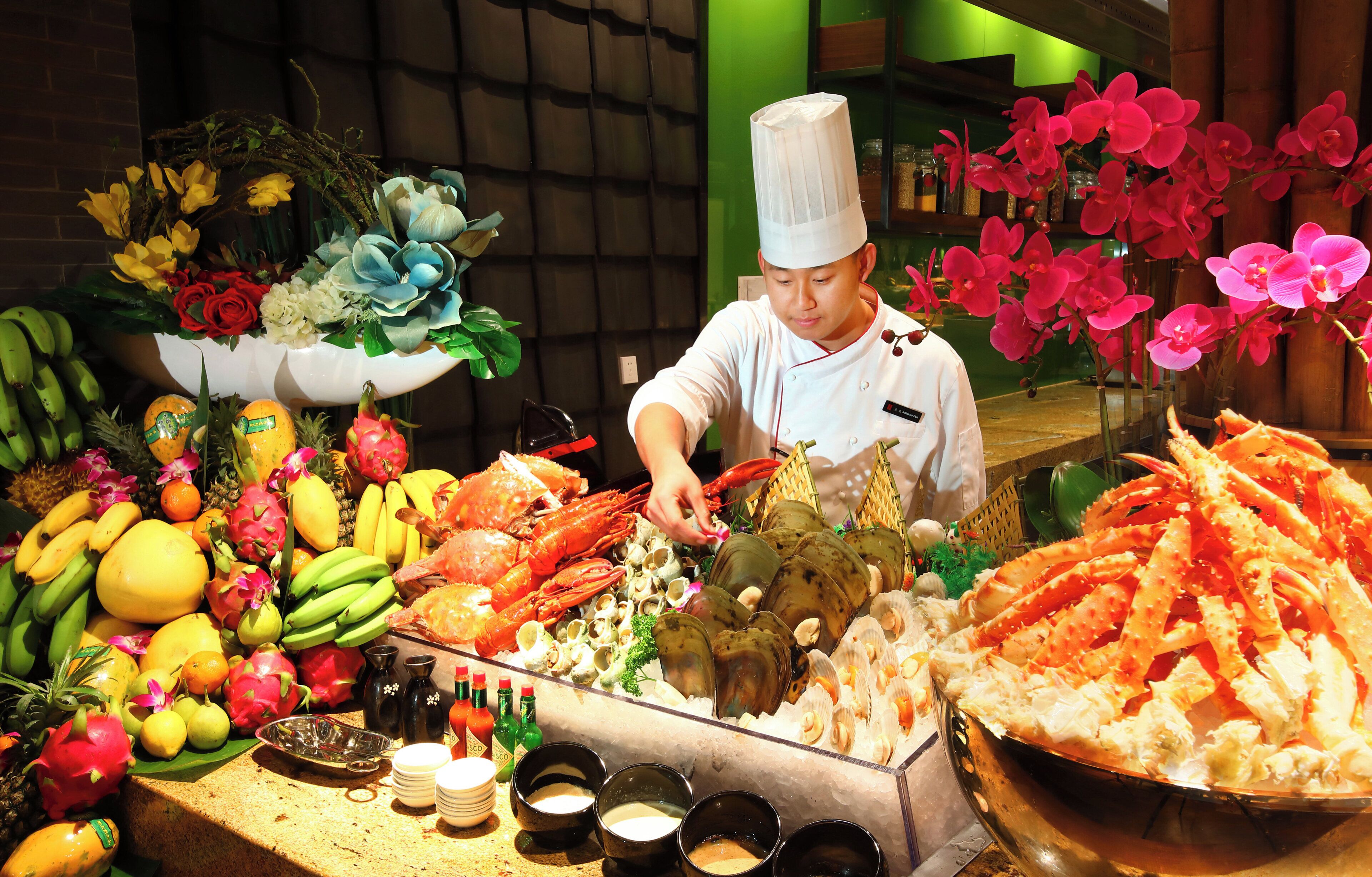 A seafood display with various types of shellfish and a chef preparing food.