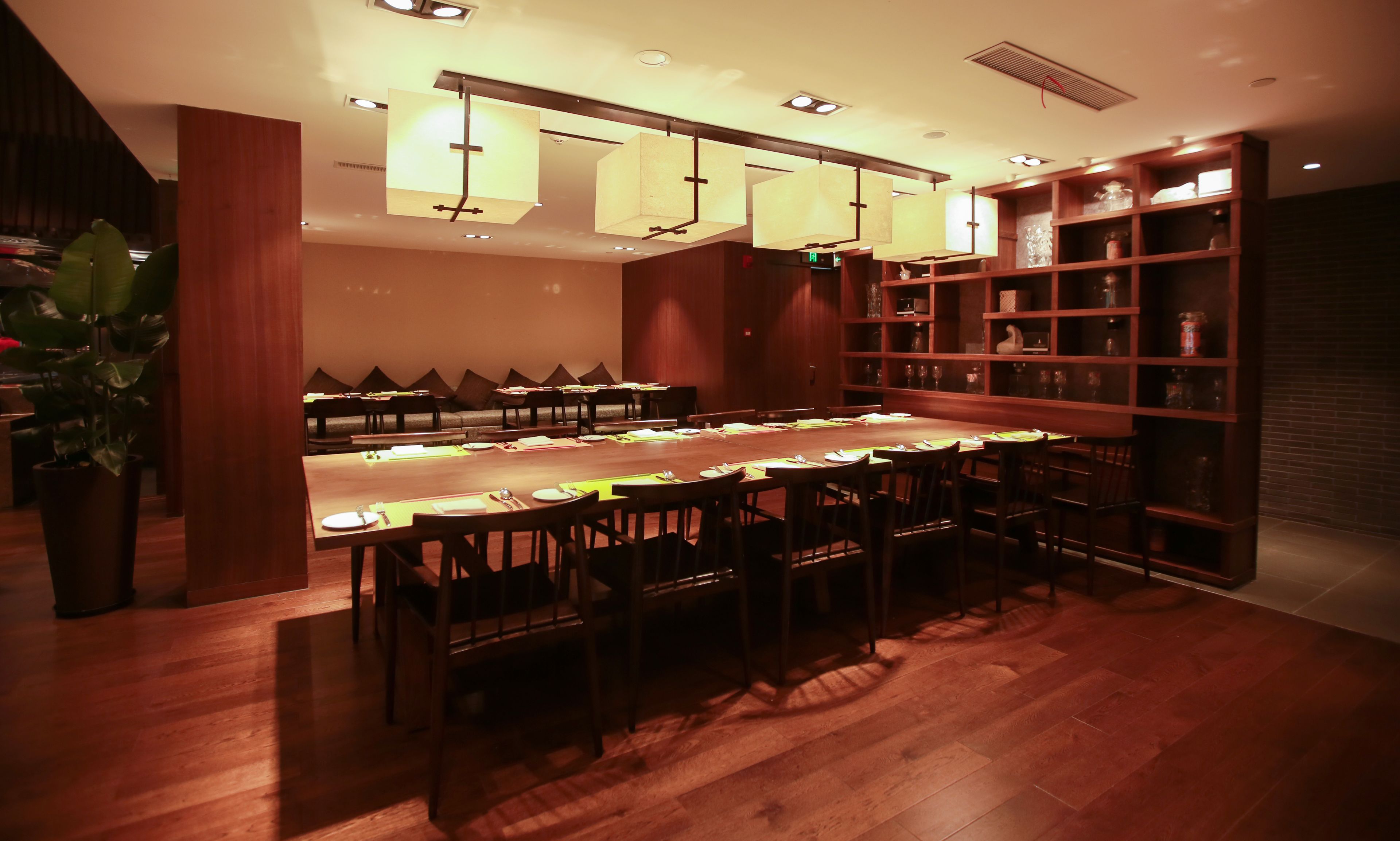 A restaurant with a long wooden table set for dining, surrounded by chairs.