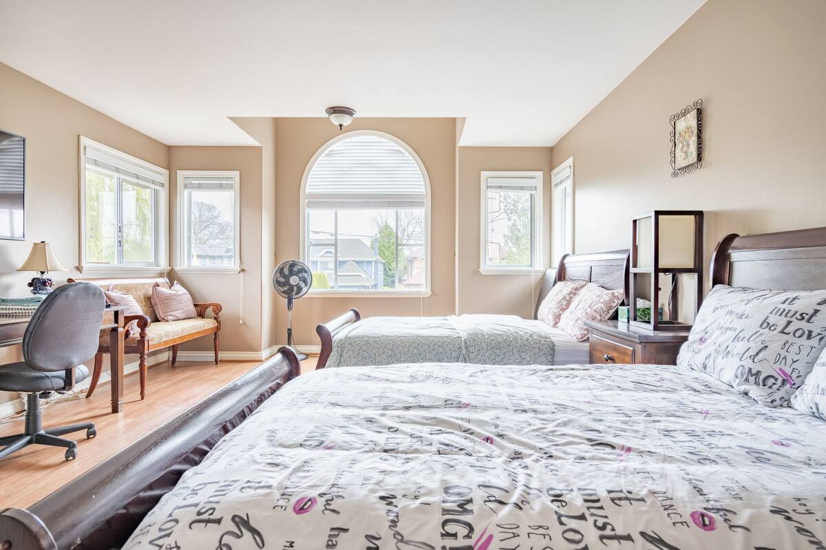 Un dormitorio con dos camas, un escritorio, una silla y un ventilador.