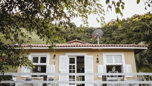 A two-story house with a satellite dish, white shutters, and a white fence. - Pousada Monteiro (Valenca)