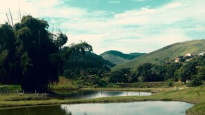 A tranquil pond surrounded by lush greenery and hills in the background. - Pousada Monteiro (Valenca)