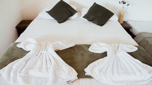 A neatly made bed with two pillows, a vase with flowers, and two towels on the bed. - Pousada Monteiro (Valenca)