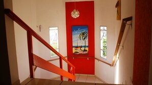 Una escalera con un muro rojo y un cuadro de una playa.