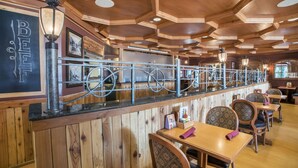 L’intérieur d’un restaurant est agrémenté de lambris en bois, il comprend un bar et plusieurs tables et chaises.