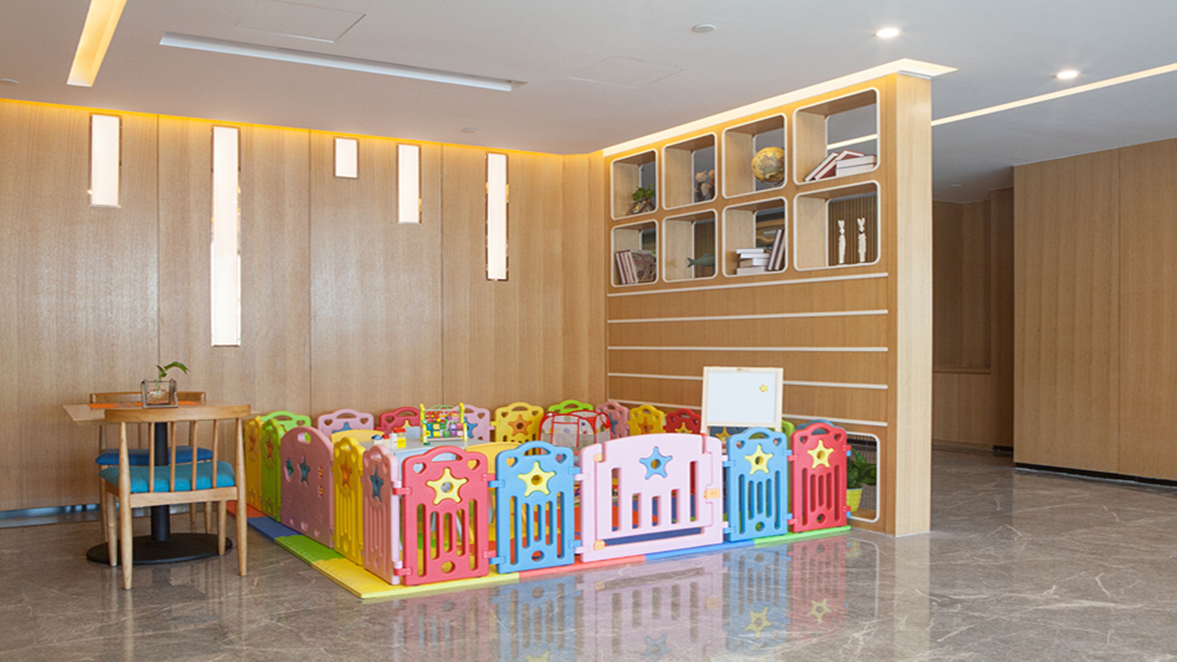 Un área de juegos infantiles con estructuras de juego coloridas y una pared de madera con estantes.
