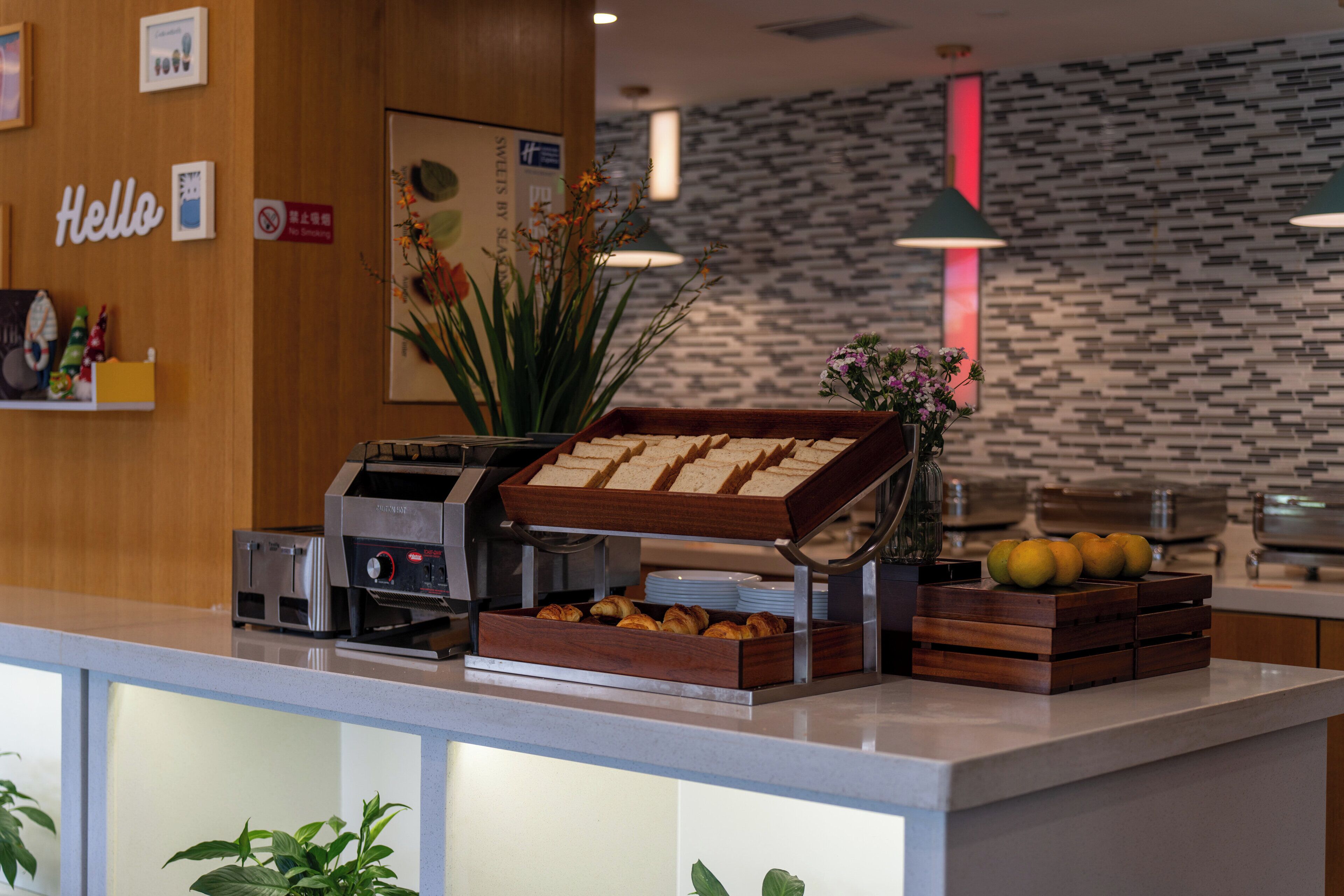 A breakfast bar with a coffee machine, pastries, and fruits.
