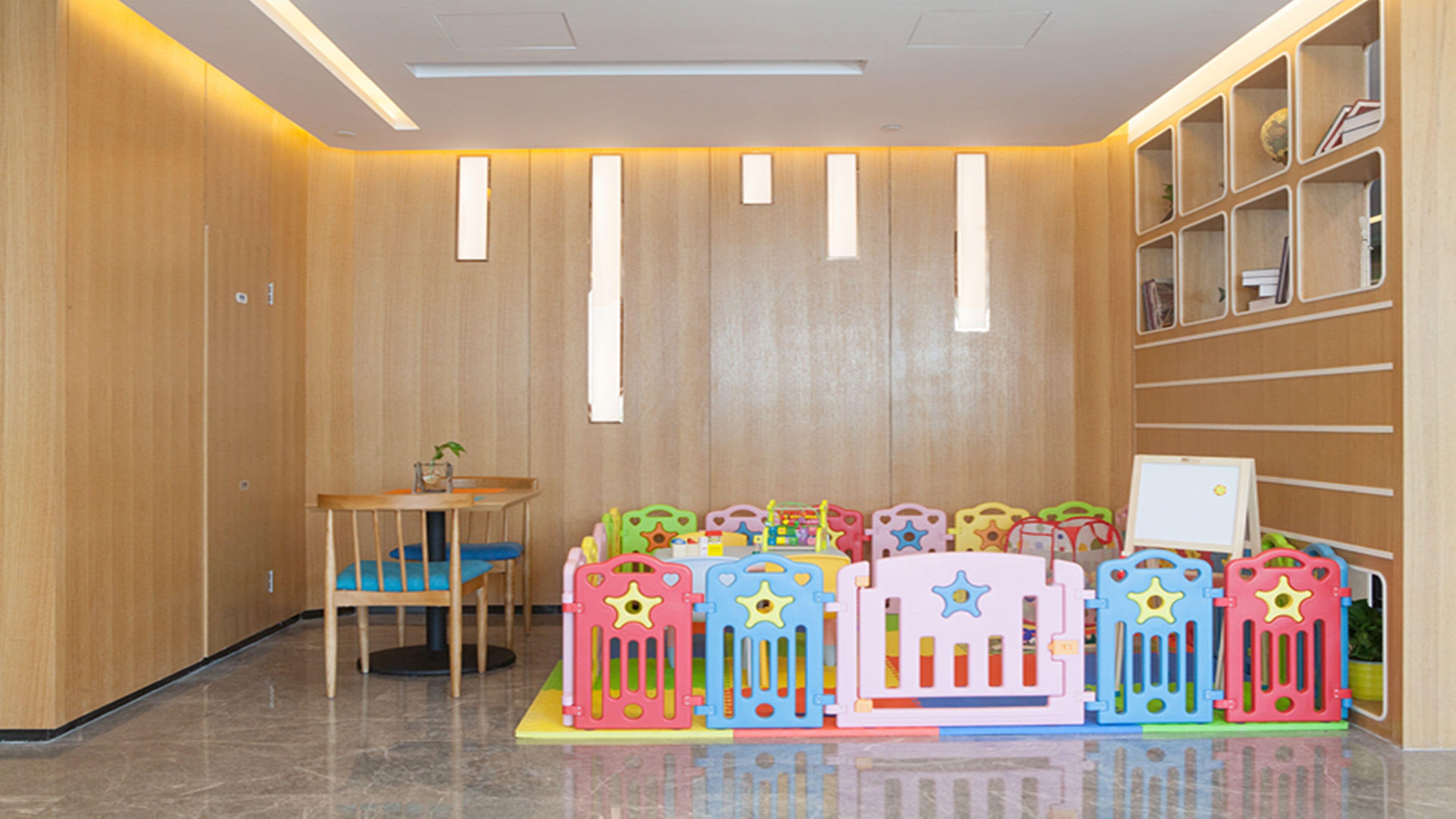 Un área de juegos infantiles con estructuras de juego coloridas y una pequeña mesa con sillas.