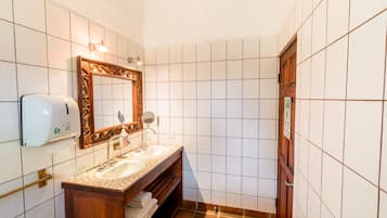 A bathroom with two sinks, a mirror, a soap dispenser, and a towel rack.