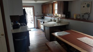 A kitchen with wooden cabinets, a countertop, a sink, and a dining area with a bench. - Cozy and comfortable 3 bedroom.   (Alton)