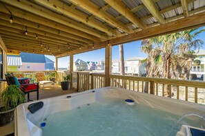 Une terrasse en bois avec un jacuzzi, des plantes en pot et du mobilier d’extérieur.