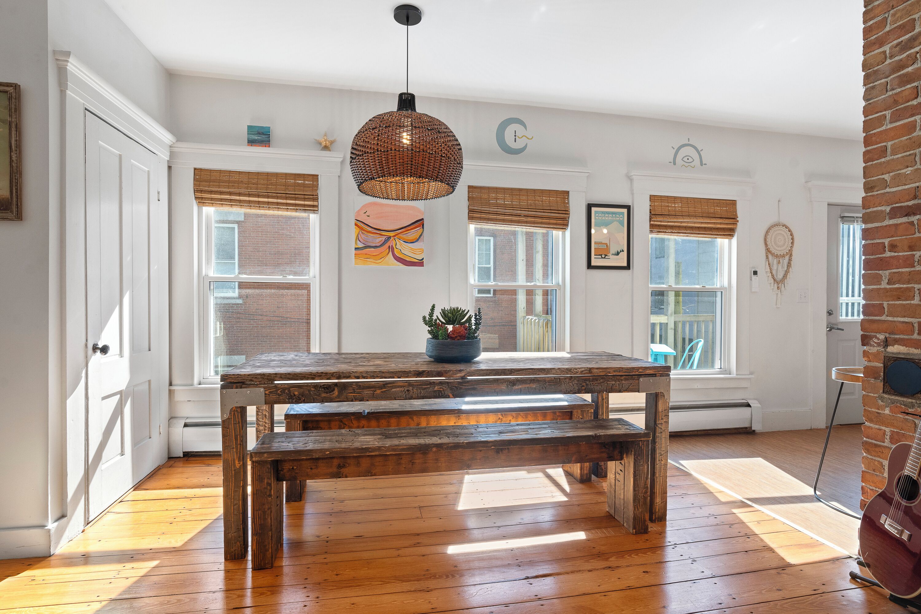 A spacious room with a large wooden table, benches, and a hanging light fixture.