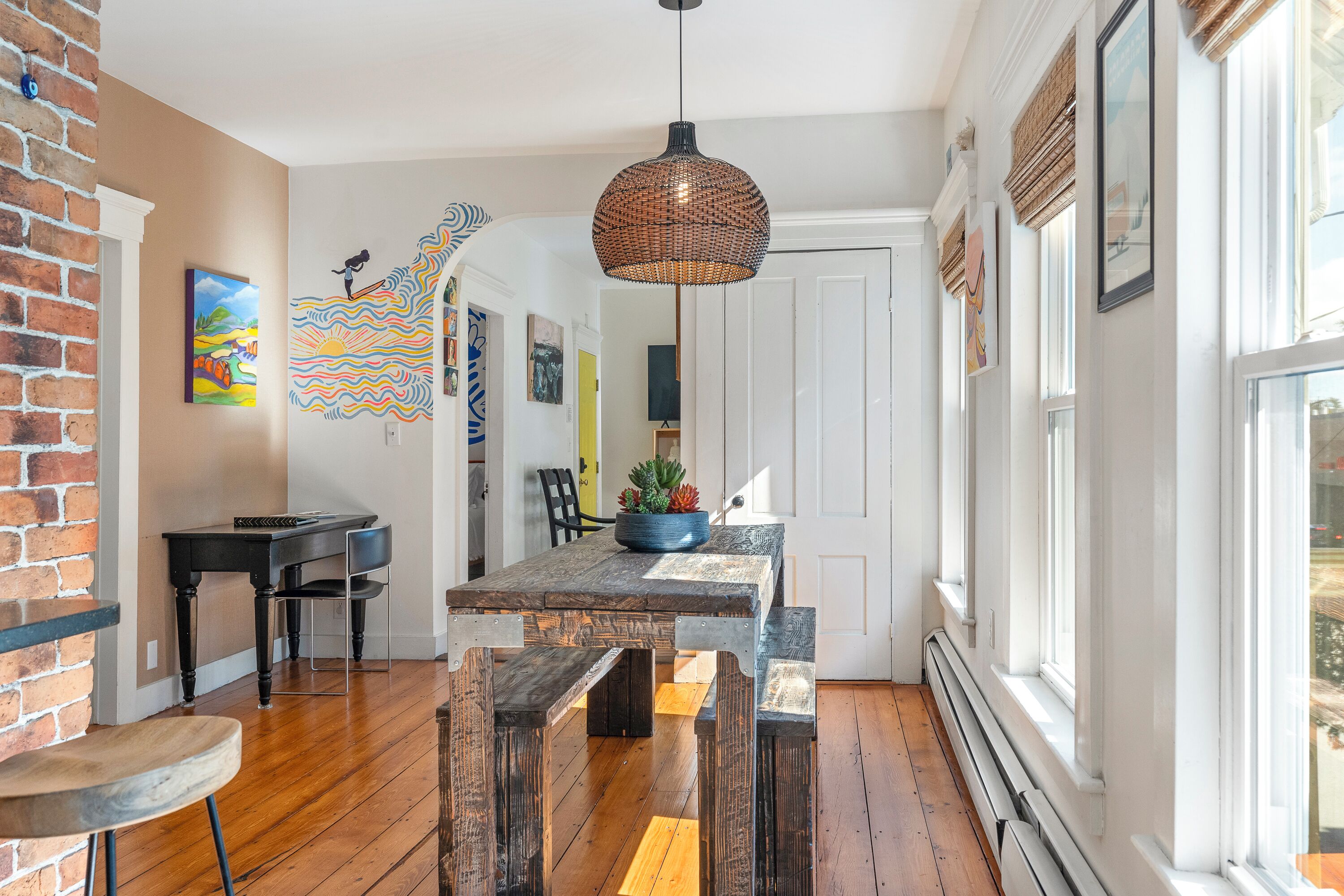 A dining area with a rustic wooden table, benches, and a hanging light fixture.