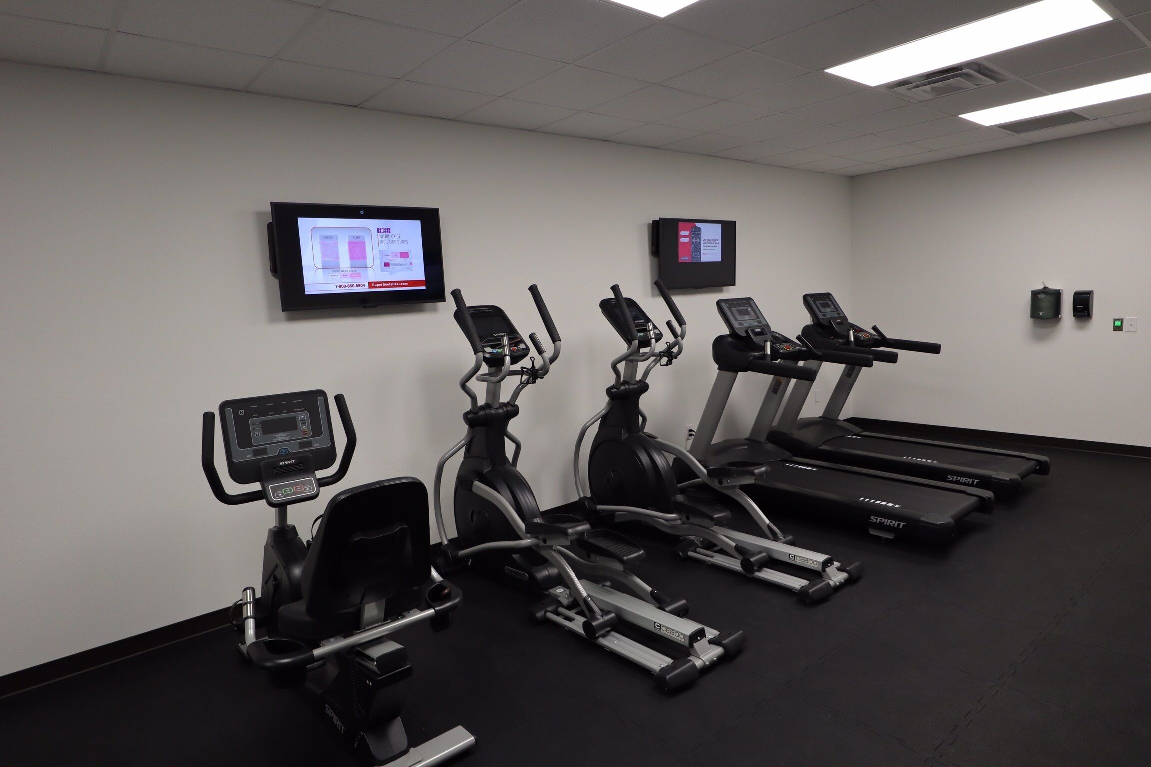 Een sportschool met loopbanden, crosstrainers en een hometrainer.