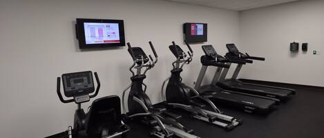 Een sportschool met loopbanden, crosstrainers en een hometrainer.