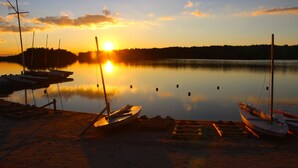 Un lago tranquilo al atardecer con barcos amarrados en la orilla.