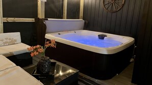 Un cuarto de spa con un jacuzzi, paredes de madera y una rueda decorativa.