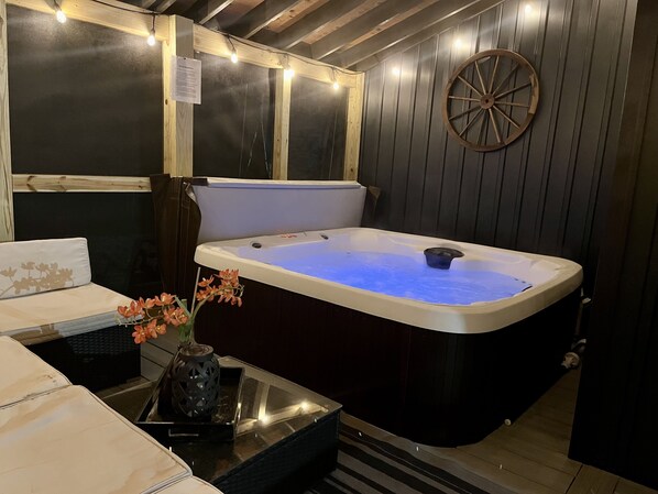 Un cuarto de spa con un jacuzzi, paredes de madera y una rueda decorativa.