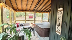 Un espacio al aire libre cubierto con techo de madera, ventilador de techo, jacuzzi y un letrero que dice "WELCOME TO OUR HOME".