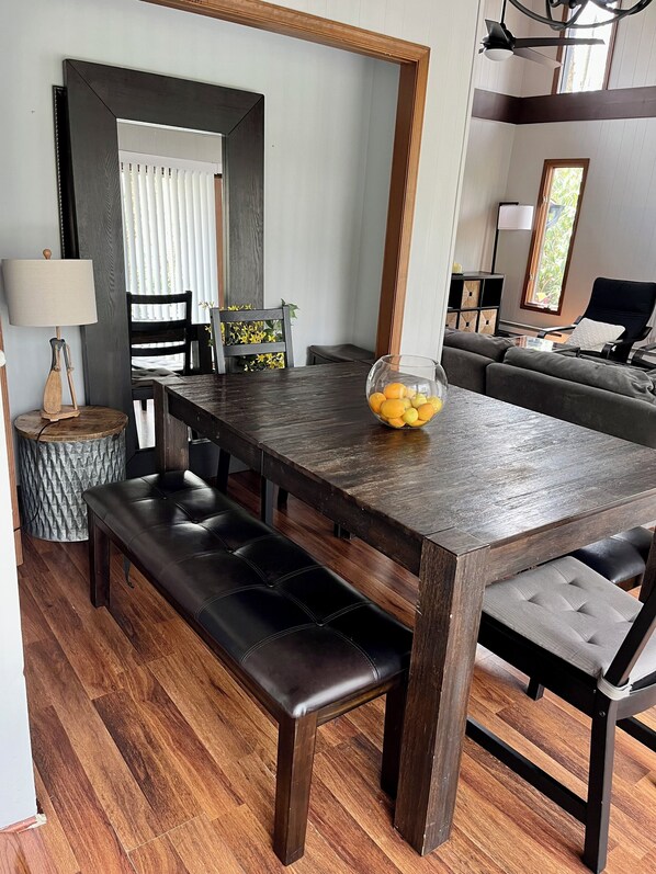 A dining area with a dark wooden table, black cushioned benches, and a glass bowl of fruit.