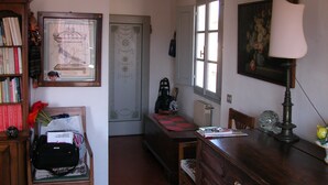 A room with a wooden desk, a chair, a bookshelf, and a door leading to another room. - Attic with views in Piazza Santa Croce (Firenze)
