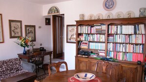 A dining area with a wooden table, chairs, a bookshelf, and a floral arrangement. - Attic with views in Piazza Santa Croce (Firenze)