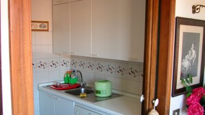 A kitchen with white cabinets, a green container, and a red dish rack. - Attic with views in Piazza Santa Croce (Firenze)