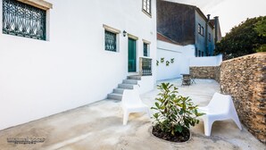 A white building with a stone wall, a staircase, and two white plastic chairs. - Apartment with Patio Centro de Ovar (Ovar)