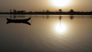 A calm lake at sunset with a boat in the foreground and a clear reflection of the sun on the water. - Apartment with Patio Centro de Ovar (Ovar)