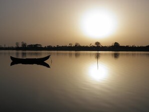 A calm lake at sunset with a boat in the foreground and a clear reflection of the sun on the water. - Apartment with Patio Centro de Ovar (Ovar)