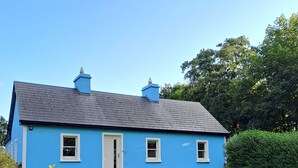 A blue house with a sloped roof, a front door, and two windows.