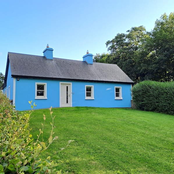 A blue house with a sloped roof, a front door, and two windows. - Family & Pet Friendly Restored Cottage in East Mayo with  4* Bord Failte Award (Bracklagh,  Brickens, Claremorris, Co Mayo)