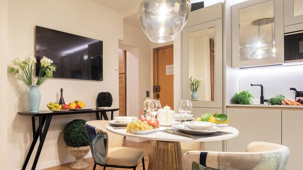 A modern dining area with a round table, chairs, a TV, and a kitchen in the background. - Tuscany Viareggio exclusive beachfront apartment   (Viareggio)