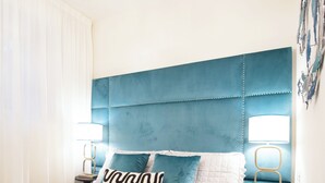 A neatly made bed with teal and white bedding, two pillows, and a folded towel. There are two bedside tables with lamps, and a wall-mounted artwork. - Tuscany Viareggio exclusive beachfront apartment   (Viareggio)
