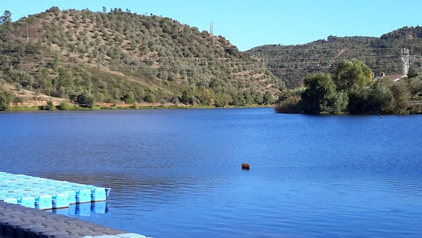 Ein ruhiger See mit einem Holzsteg, der ins Wasser ragt.