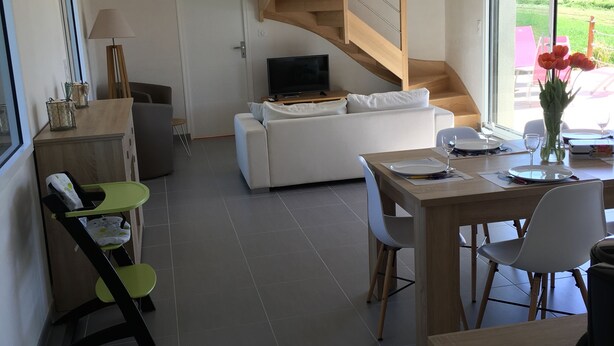 Un salon moderne avec un escalier, un coin repas et une vue sur un jardin.