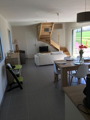 Un salon moderne avec un escalier, un coin repas et une vue sur un jardin.