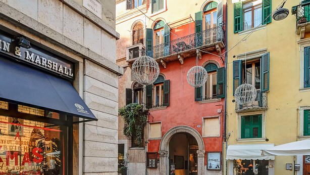 Una calle adoquinada con edificios de arquitectura tradicional, incluyendo un escaparate con un letrero que dice "MARSHALL".