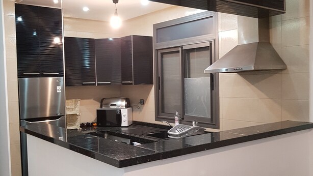 A modern kitchen with a central island, stainless steel appliances, and black cabinetry. - 3 modern new rooms with satelite wifi and air conditioning (agadir)