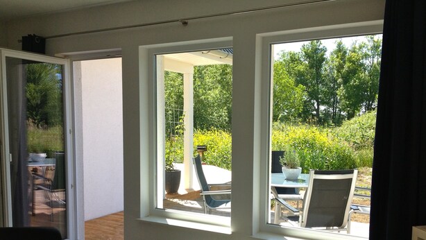 A room with a table and chairs, large windows with a view of greenery outside. - Beautiful, natural flat with big terrace in the heart of the island of Rügen (Patzig)